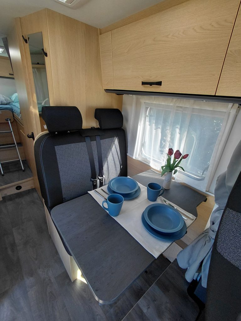 Gemütliche Sitzgruppe mit Esstisch im Wohnmobil, gedeckt mit Geschirr und Tulpen